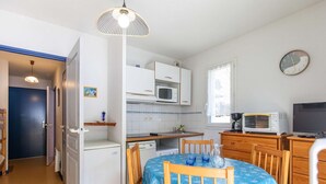 A compact kitchen with a dining area, white cabinets, a microwave, a coffee maker, and a clock on the wall. - Apartment Cauterets, 1 bedroom, 4 persons (Cauterets)