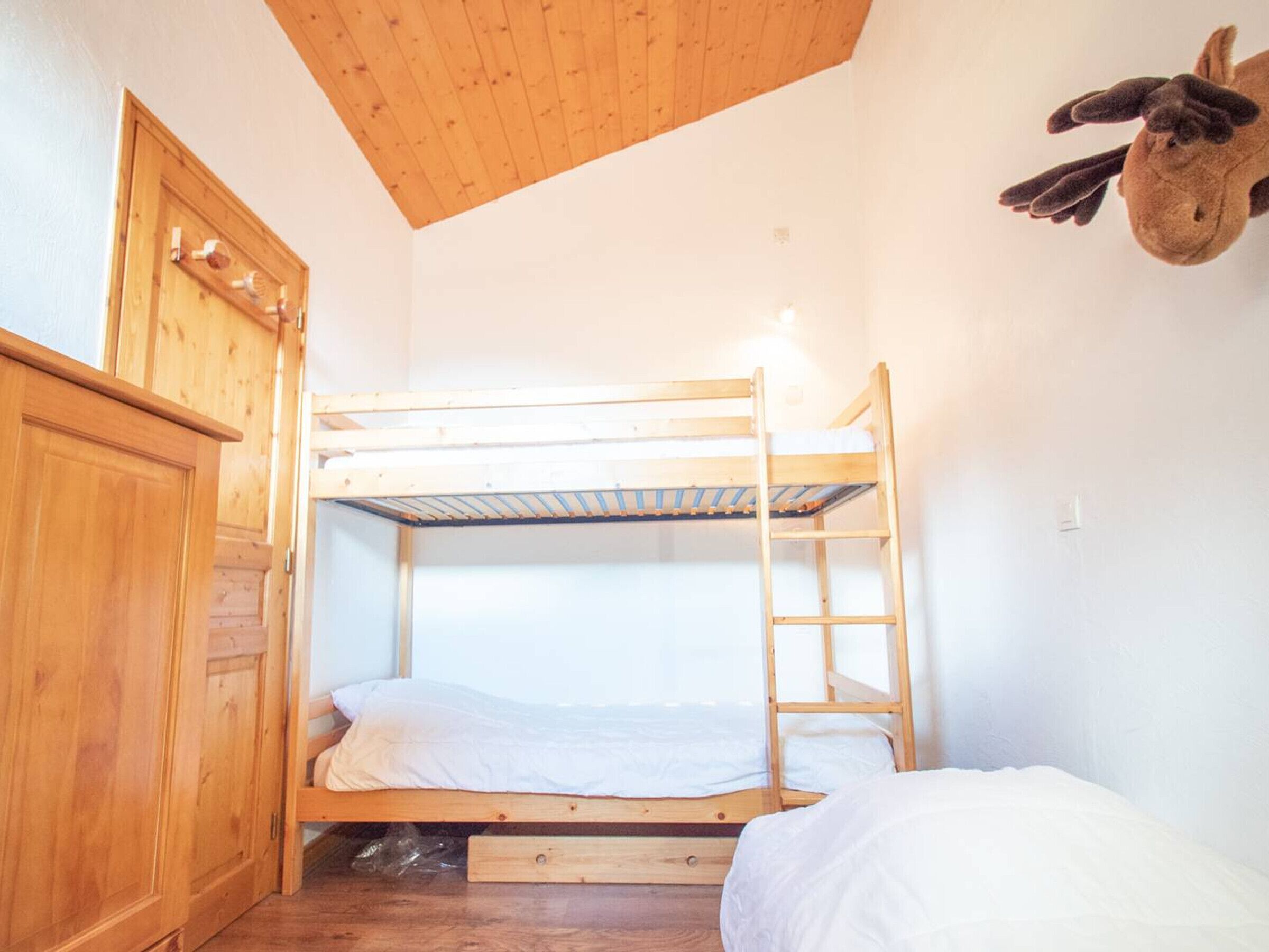 A bunk bed room with wooden walls and a ceiling.