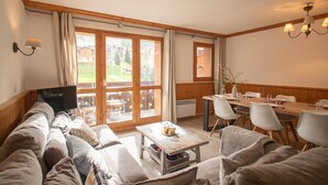 A cozy living room with a sofa, a coffee table, and a dining area with chairs and a table. - Renovated 4-room duplex, 6 pers., 2 balconies, ski locker, cleaning included (Valmorel)