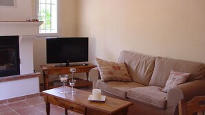 A living room with a beige sofa, a wooden coffee table, a flat-screen TV, and a fireplace.