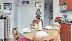 A dining area with a round wooden table set for four, surrounded by wooden chairs. A white door with a decorative mirror hangs above the table. - Cozy 4-Person Apartment in Central Cauterets, Close to Ski Lift, Spa, and Amenities (Cauterets)