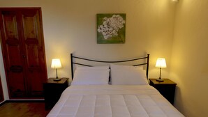 A neatly made bed with white bedding, two bedside tables with lamps, and a wooden door. - Casa Punta Amore - WelcHome (Cannobio)