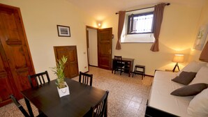 A room with a dining table, chairs, a sofa, a lamp, and a window with curtains. - Casa Punta Amore - WelcHome (Cannobio)