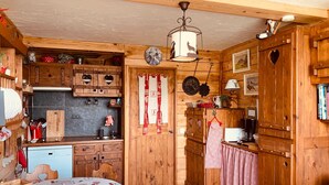 Una cocina acogedora con armarios de madera, una mesa de comedor con mantel a cuadros y un taburete de madera.