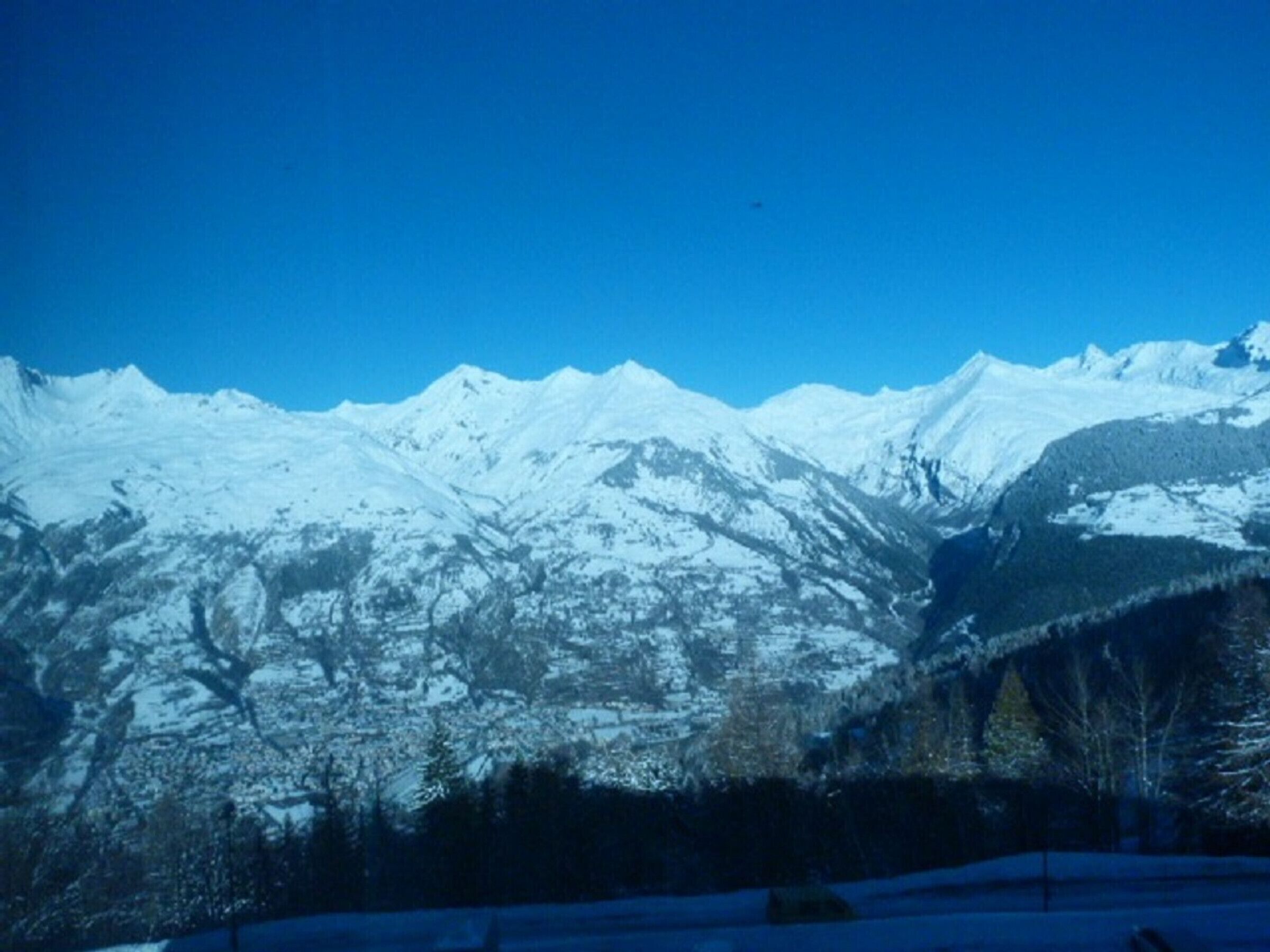 Ein mit Schnee bedecktes Gebirge unter blauem Himmel.