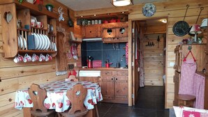 Interior acogedor de una cabaña de madera, con mesa, sillas y una zona de cocina.