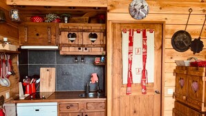 Una cocina rústica con armarios de madera, lavavajillas y un reloj en la pared.