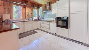 A modern kitchen with wooden ceiling, white cabinets, and a Bosch oven. - CHALET CHEBOURINS - 8 PERS - 3 BEDROOMS - WIFI - MONTRIOND (Montriond)
