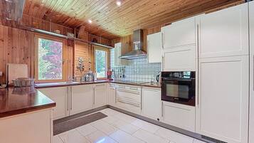A modern kitchen with wooden ceiling, white cabinets, and a Bosch oven.