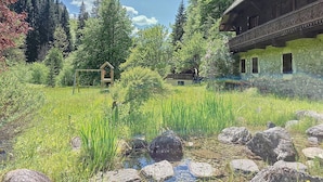 A rustic cabin with a balcony, surrounded by a lush garden and a small pond. - CHALET CHEBOURINS - 8 PERS - 3 BEDROOMS - WIFI - MONTRIOND (Montriond)