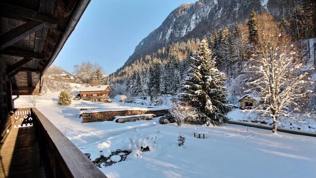 A wooden cabin with a snow-covered landscape, a stone wall, and a mountain in the background. - CHALET CHEBOURINS - 8 PERS - 3 BEDROOMS - WIFI - MONTRIOND (Montriond)