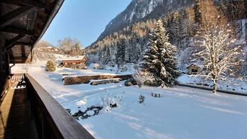 Une cabane en bois, avec un paysage enneigé, un mur de pierre et une montagne en arrière-plan.