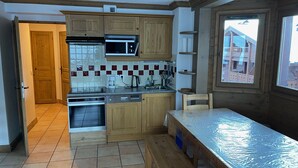 A compact kitchen with wooden cabinets, a microwave, a coffee maker, and a dishwasher. - C301 - 60 m2 - 3P+Cab - 6/8 pers (Prapoutel)
