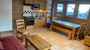 A compact kitchen with wooden cabinets, a microwave, and a coffee maker. There is a dining table with chairs and a bench. - C301 - 60 m2 - 3P+Cab - 6/8 pers (Prapoutel)