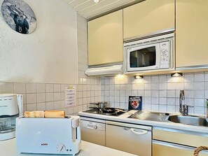 A compact kitchen with a toaster, a stove, a microwave, and a sink.