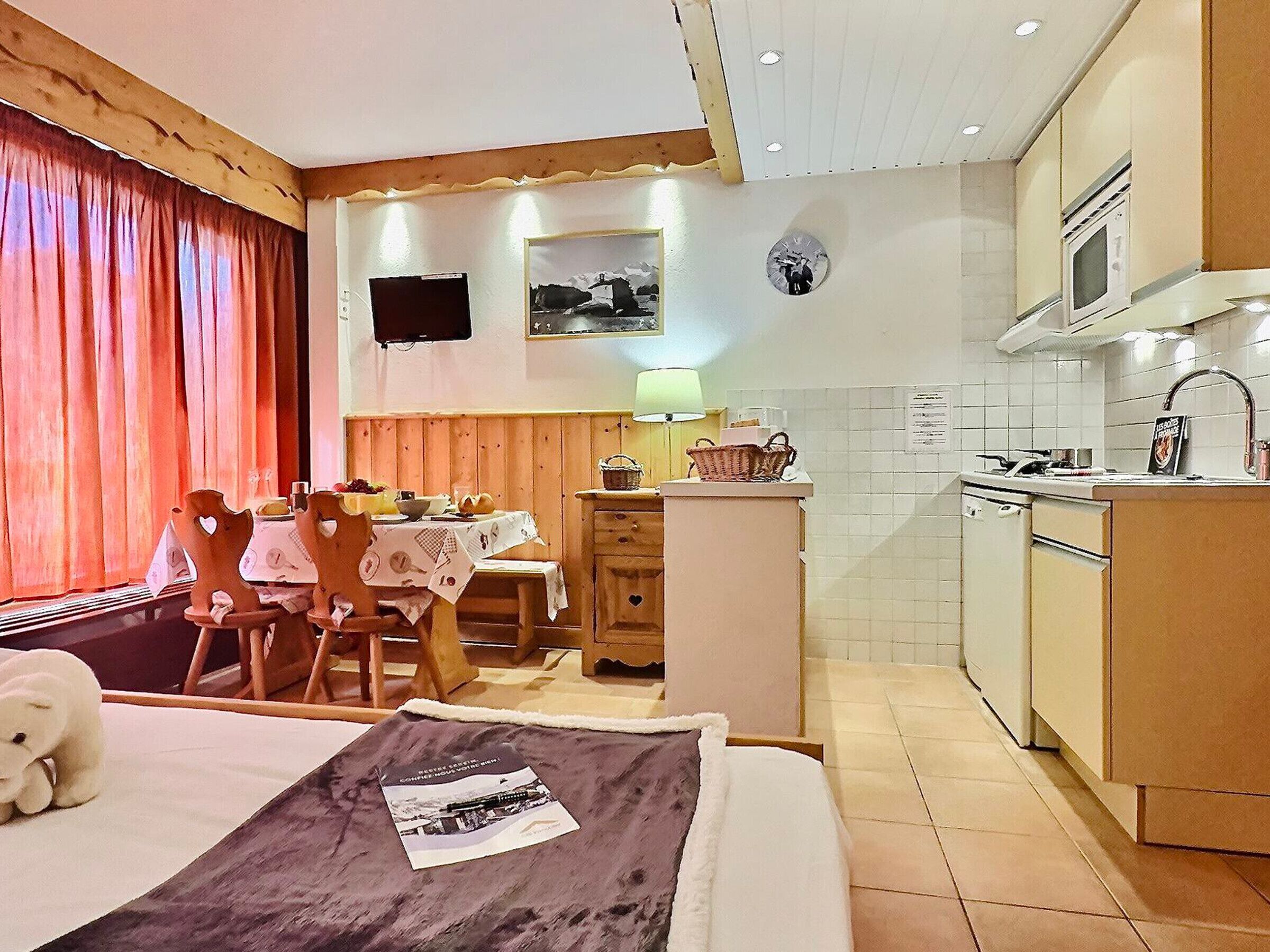 Una camera accogliente con un letto, un tavolo da pranzo, un angolo cottura e una televisione.