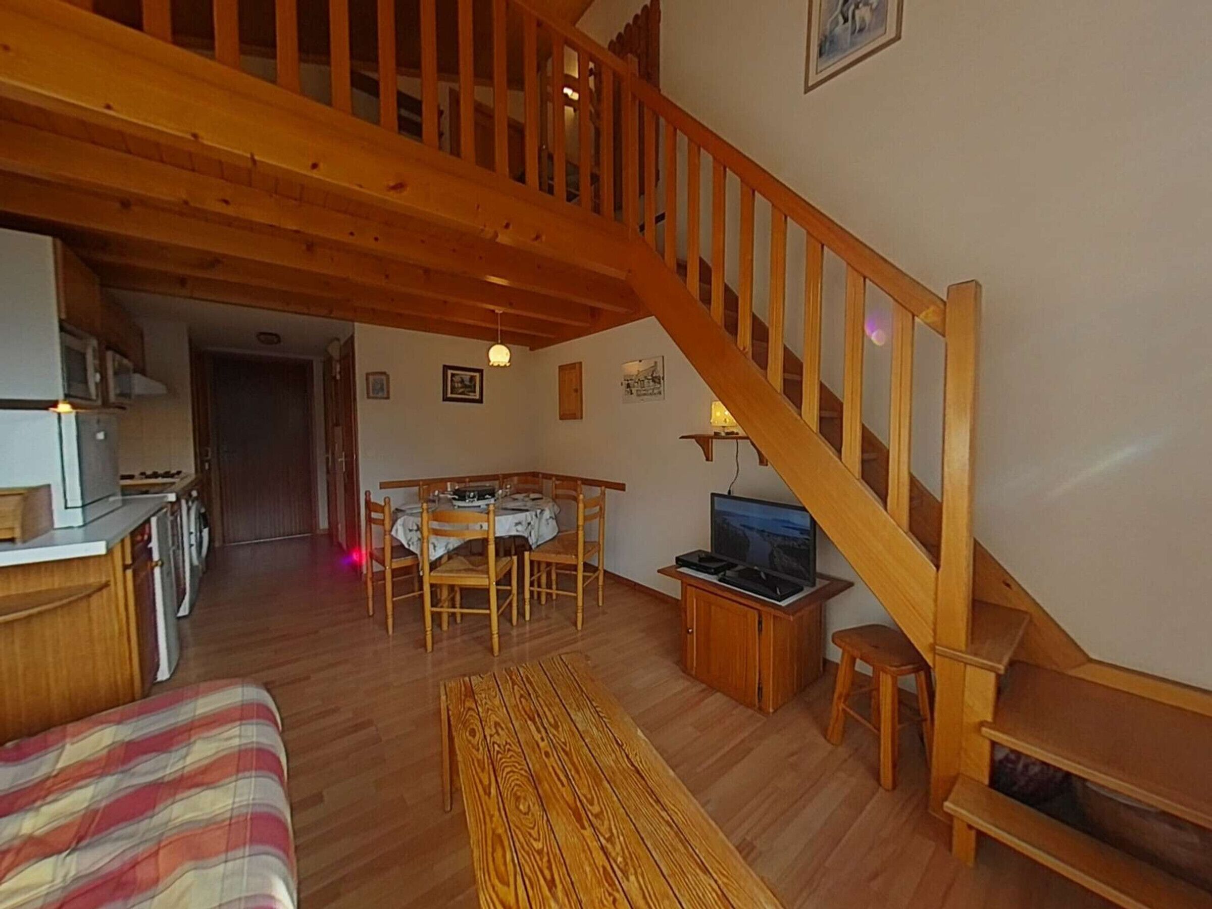 Uma sala de estar acolhedora com escada de madeira, área de jantar e cozinha.