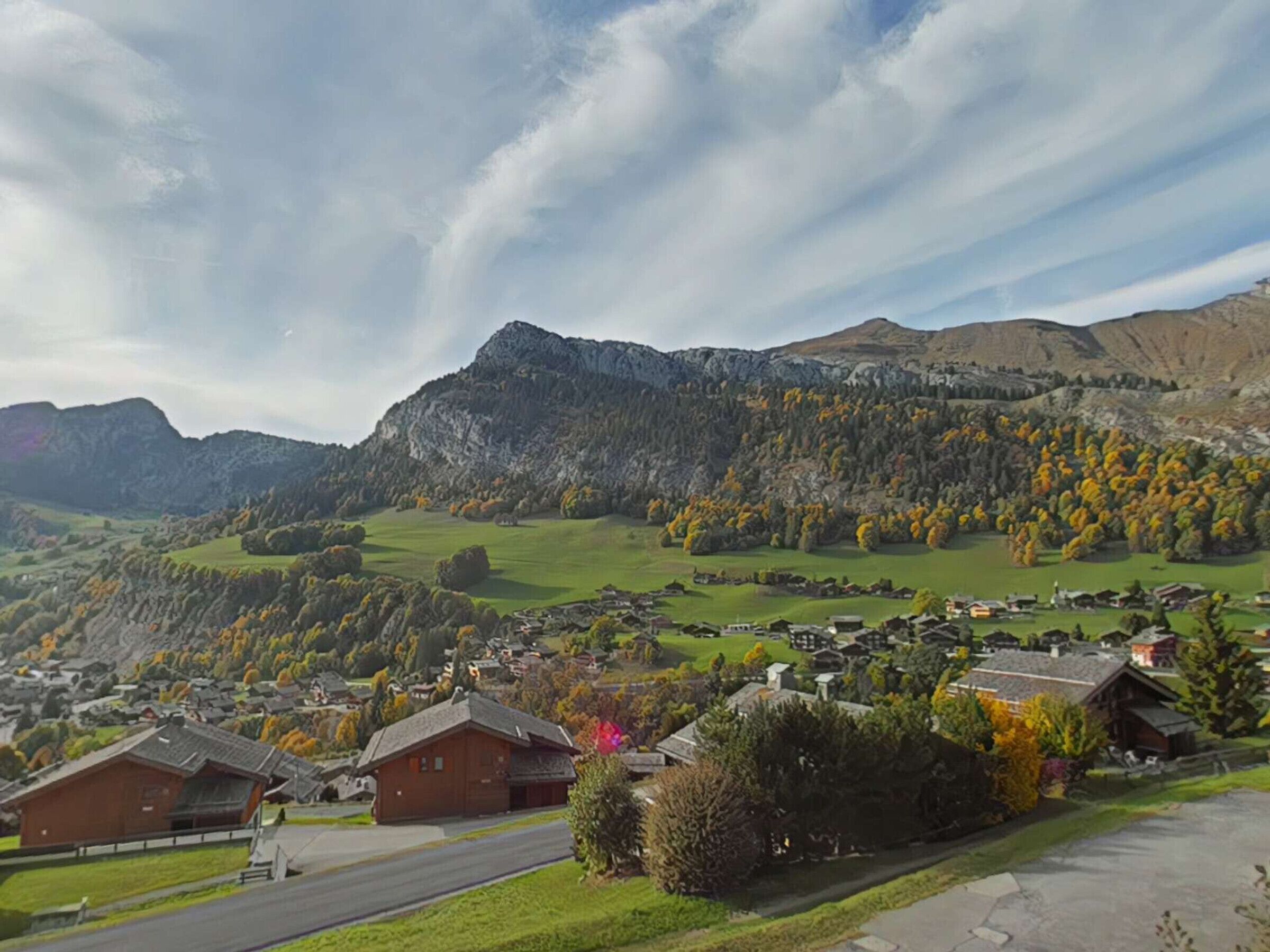 Un paisaje montañoso con un pequeño pueblo, casas y una carretera.