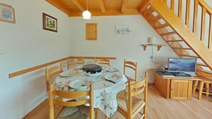 A dining area with a wooden table set for four, surrounded by wooden chairs. A wooden staircase leads to an upper level. - Apt 2BR + loft for 6 - ski-in/ski-out - garage - WIFI (Le Grand-Bornand)