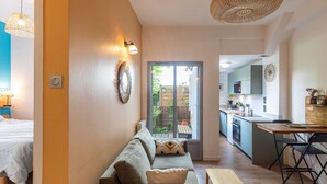 A modern living room with a sofa, a small table, and a kitchen area with a bar stool.