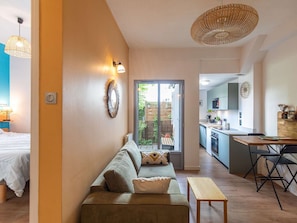 A modern living room with a sofa, a small table, and a kitchen area with a bar stool.