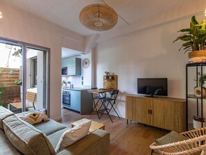 A modern living space with a sofa, a dining table, a TV, and a kitchen area. - **Cozy 1-BR Apartment for 4 with Terrace, 200m to Ski Lift, Central** (Cauterets)