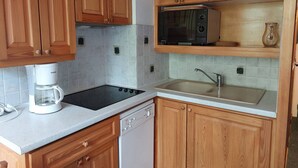 A compact kitchen with wooden cabinets, a microwave, a coffee maker, and a dishwasher. - Cozy duplex for 4 near slopes at Arcs 1800 (Les Arcs 1800)