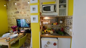 Cocina compacta con microondas, un refrigerador pequeño y una zona de comedor con mesa y sillas.