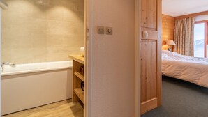 Une salle de bain avec une baignoire, une étagère en bois et des toilettes.