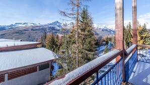 Un balcon offrant une vue sur des montagnes enneigées et un ciel dégagé.