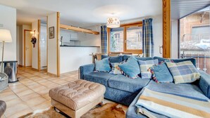 Una sala de estar acogedora con sofá, reposapiés y una zona de comedor con mesa y sillas.