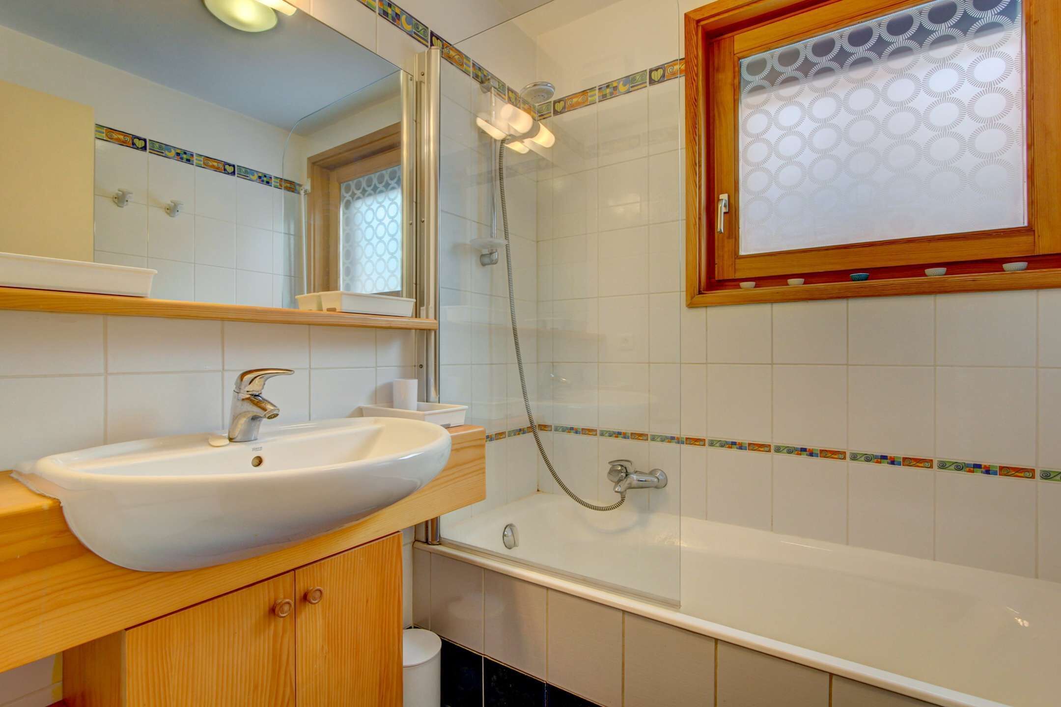 Une salle de bain avec un lavabo blanc, un miroir, une douche et une baignoire.
