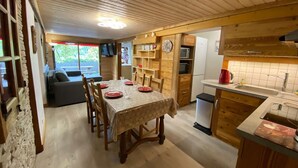 Una cucina accogliente con mobili in legno, un tavolo da pranzo per quattro persone e un piccolo frigorifero.