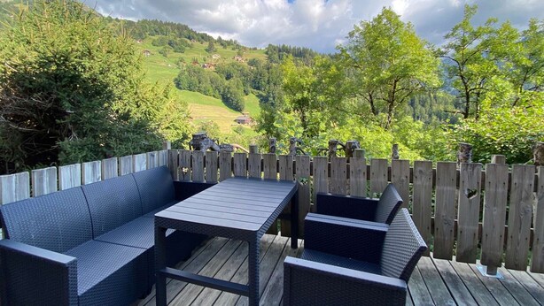 Una terrazza con mobili in vimini e vista su un paesaggio verde.