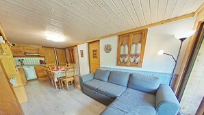 Un'accogliente zona giorno con un divano grigio, un tavolo da pranzo in legno e una cucina sullo sfondo.