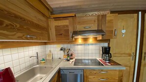 Una cucina compatta con mobili in legno, un lavello in acciaio inossidabile, una lavastoviglie e una macchina da caffè.
