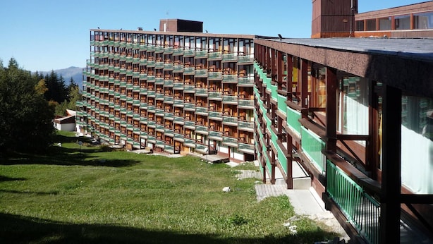 Un hotel moderno con un diseño modular único, que cuenta con varios balcones y una fachada verde destacada.