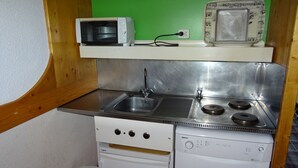 Una kitchenette compacta con microondas, fregadero, hornilla y lavavajillas.