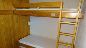 Una cama litera con escalera de madera y colchón blanco.