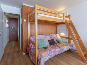 A bunk bed with a ladder, a floral sofa, and a door with a lock.