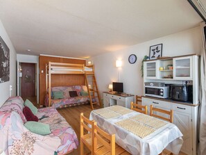 A compact room with a bunk bed, a dining table, and a kitchenette.