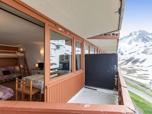 A cabin with a bunk bed, a small kitchen, a dining area, and a balcony with a mountain view.