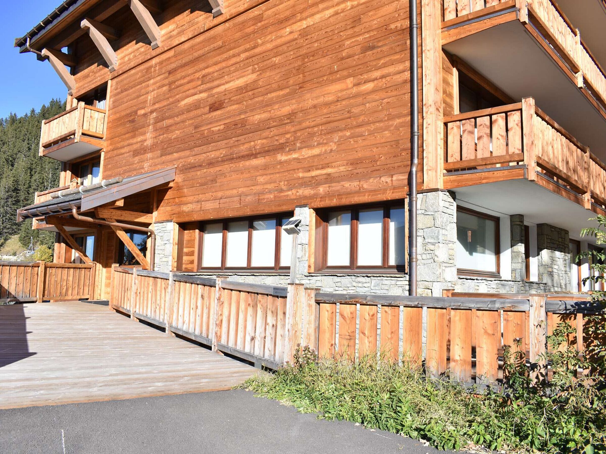 A wooden chalet with balconies, stone accents, and a wooden deck.