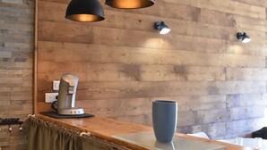 A wooden wall with a modern pendant light fixture and a coffee machine on a counter.