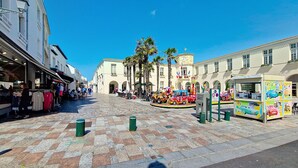 Une place agrémentée d’une tour horlogée, de palmiers et d’un carrousel aux couleurs vives.