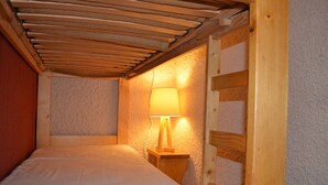 Ein kleiner, gemütlicher Raum mit einem Einzelbett, einem hölzernen Kopfteil und einem Nachttisch mit einer Lampe.