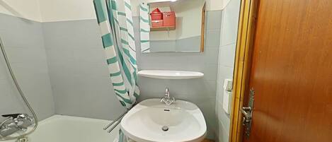 Un baño con bañera, lavabo, espejo y cortina de ducha.