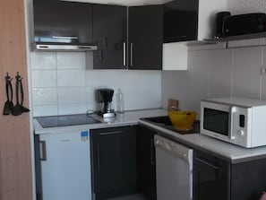 Een koelkast, een oven, een vaatwasser, kookgerei, borden en bestek