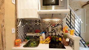 Una cocina con microondas, un lavaplatos y diversos alimentos, como plátanos y tomates.