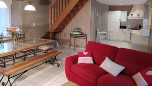 A modern living space with a dining area, a red sofa, and a kitchen.